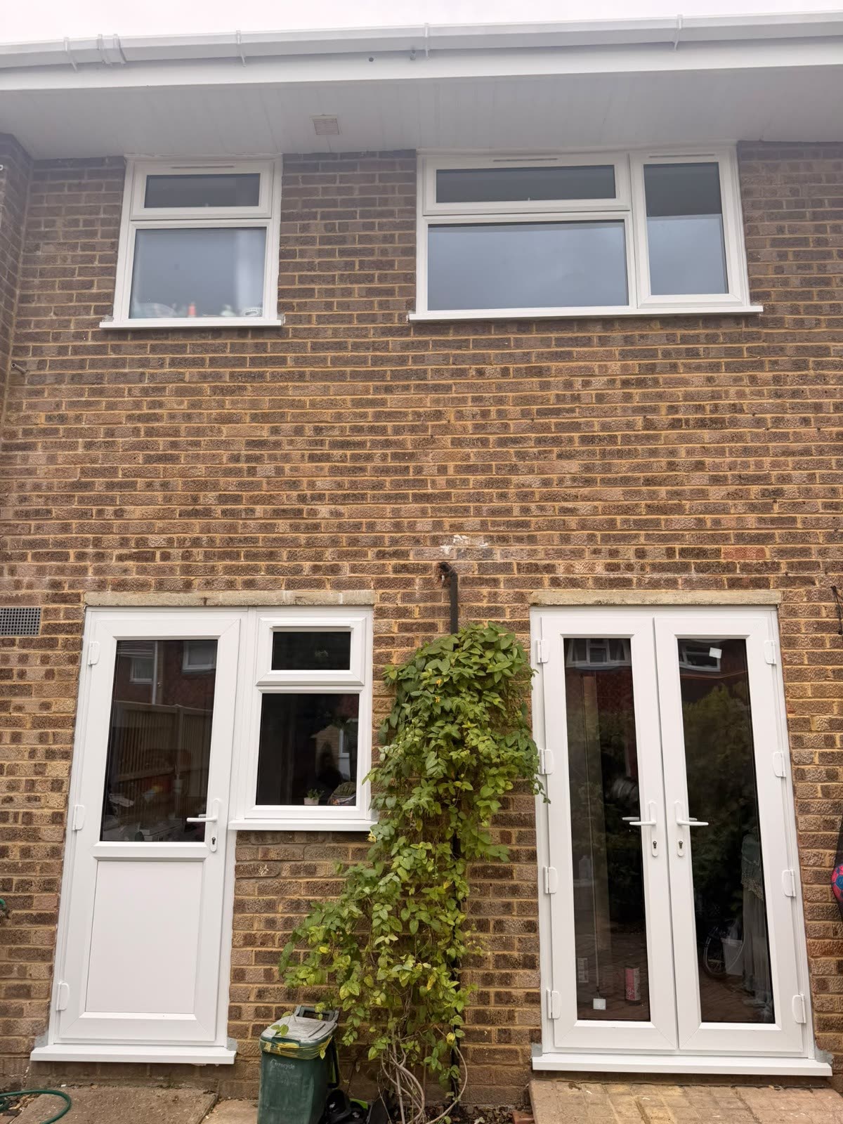 Rear of a brick house in Woking with new white uPVC windows, a back door and French doors, fitted by Termopane Windows